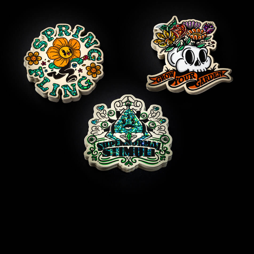 Three glitter stickers with a skull and flowers on them