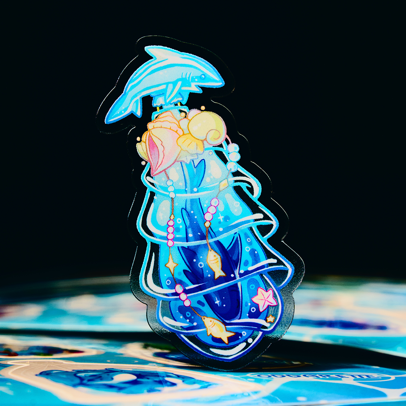 Transparent sticker from Thank You card showing a colorful dolphine and shark, set against a dark background