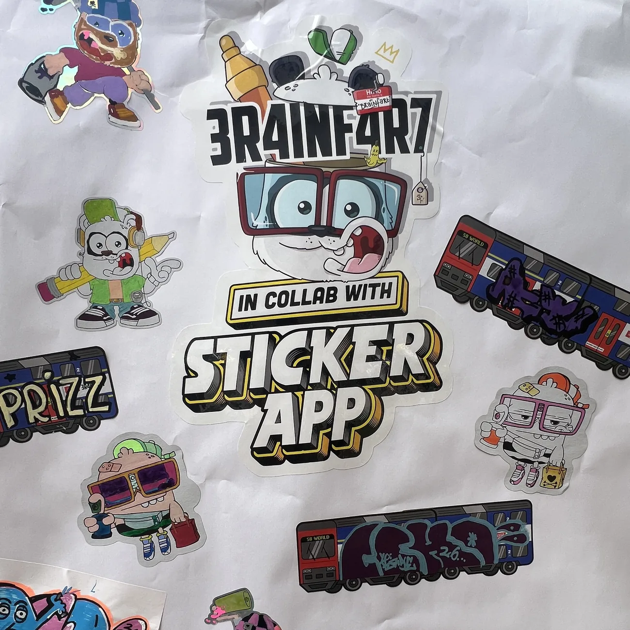 Vägg täckt av egenhändigt färglagda die-cut klistermärken från Brainfart x StickerApp och etiketter med S8 World-tåget med graffititaggar