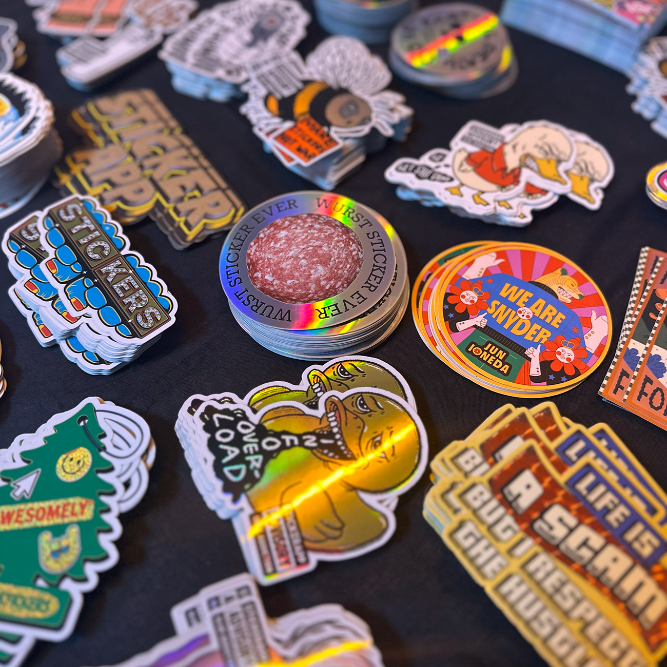 Die-cut stickers tryckta i olika material och storlekar på ett mörkt bord