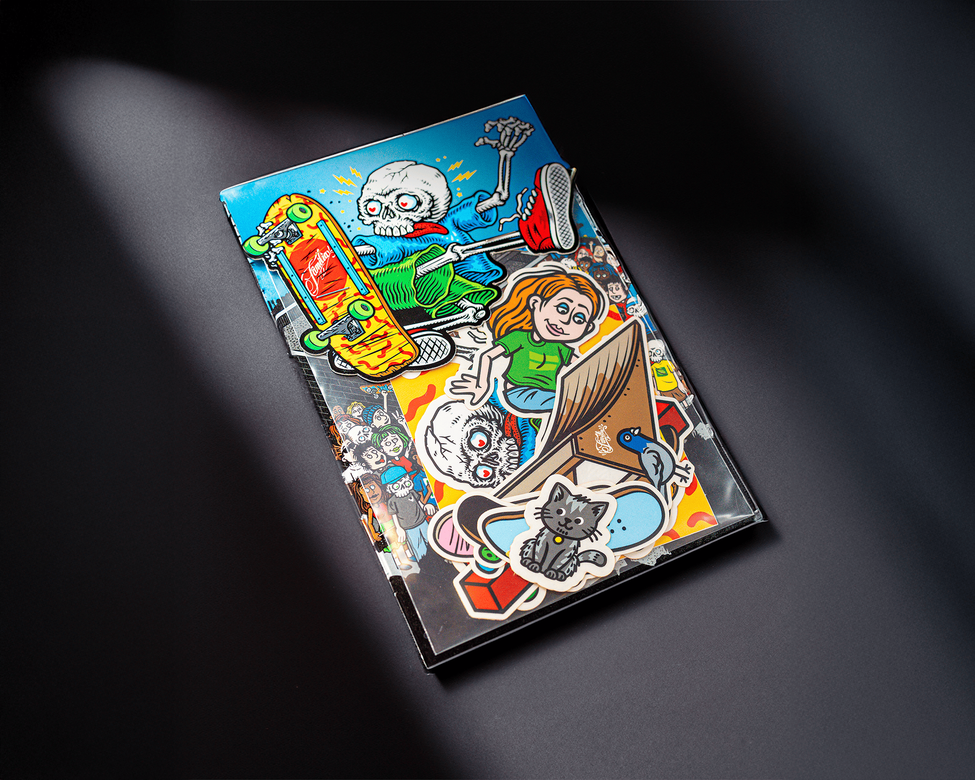 A colorful sticker pack with vibrant, cartoonish stickers featuring a skeleton, a girl on a laptop, and a cat, set against a dark background.