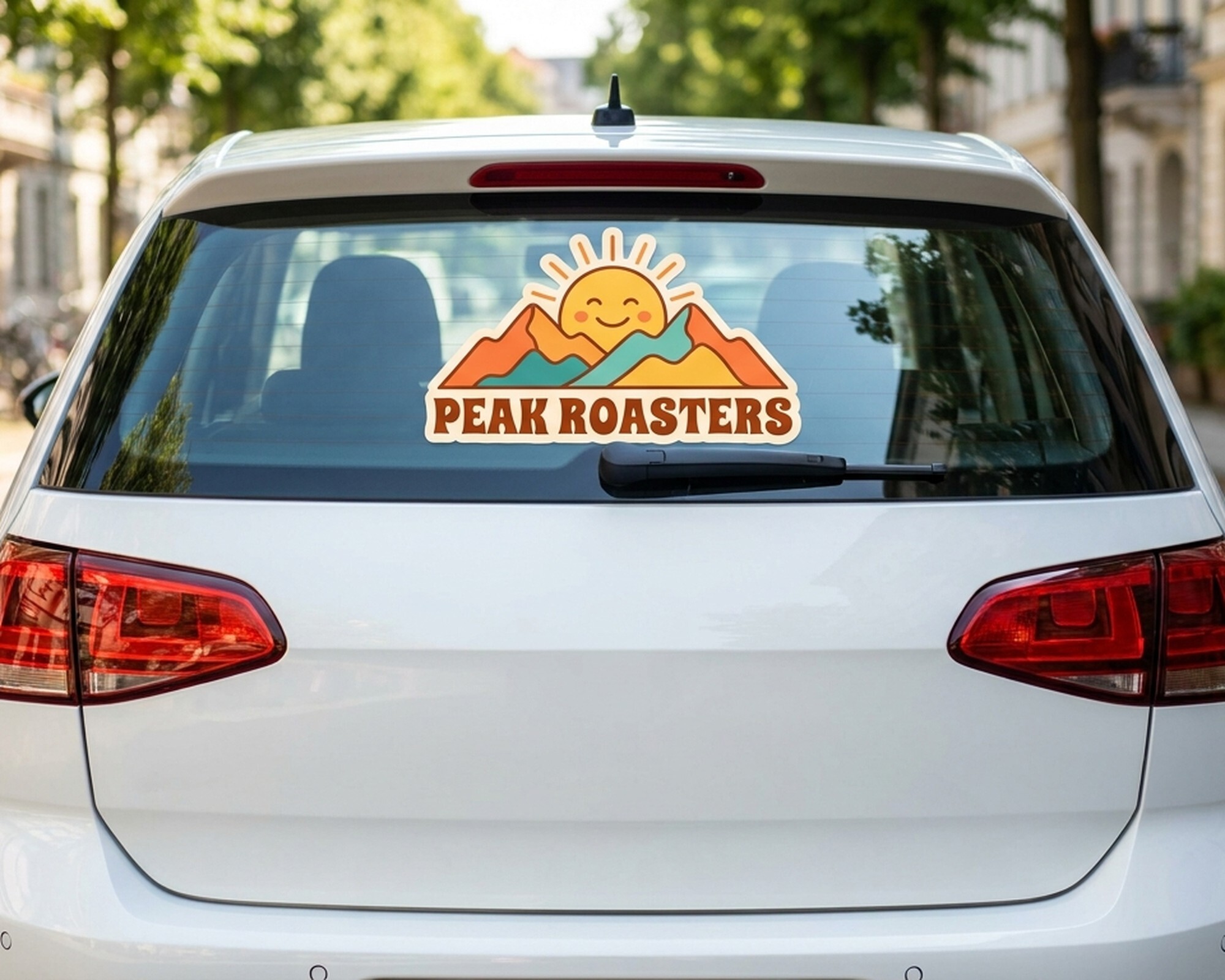 Egen dekal i die-cut med en logga med sol och berg och texten "Peak Roasters" på en bils bakruta